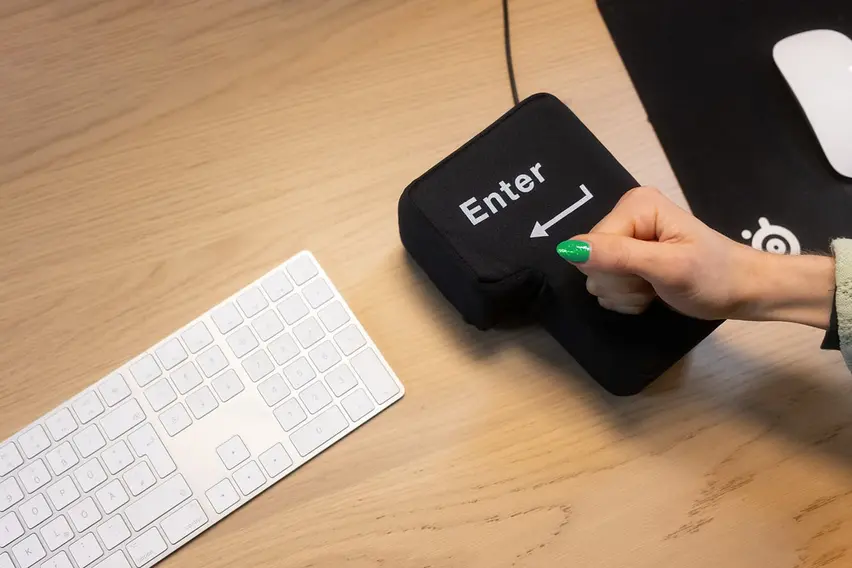 Eine Hand haut kräftig auf eine überdimensionierte Enter-Taste