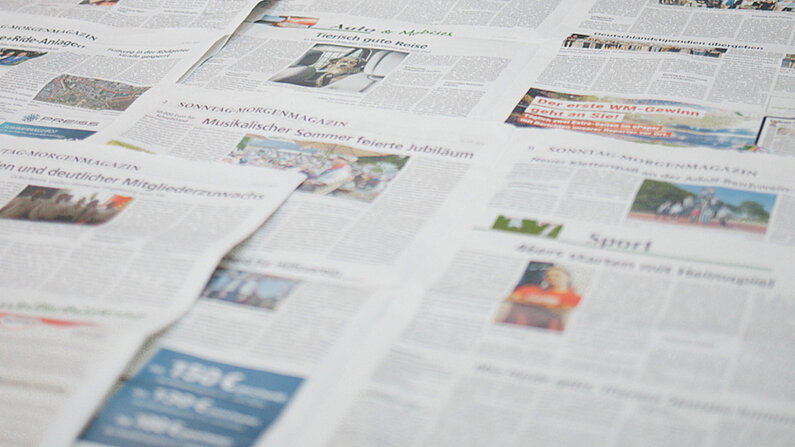 Nahaufnahme mehrerer sich überlappender Zeitungsartikel.
